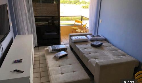 a living room with a couch in front of a window at Resort flat Gavôa in Igarassu