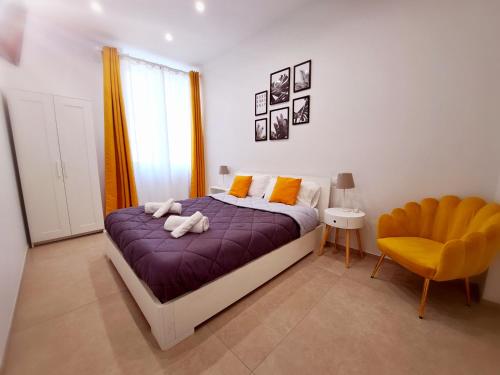 1 dormitorio con cama morada y silla amarilla en Le Popolari - Appartamento, en Bitonto