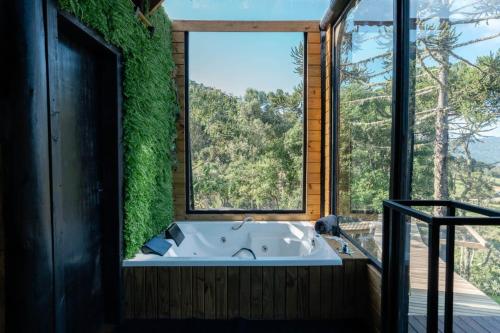 a bath tub in a room with a large window at Cabana estilo Celeiro em Urubici in Urubici