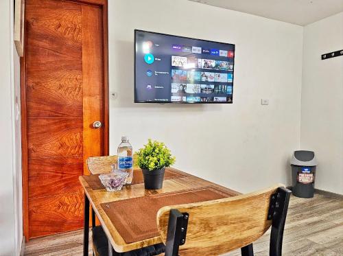 a dining room table with a television on the wall at Hospedaje Celerina & Elio in Lima