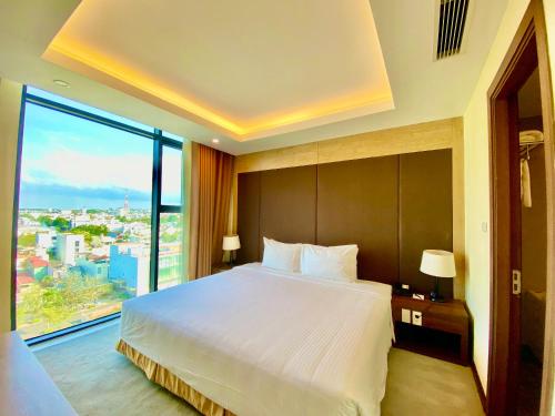 a bedroom with a large bed and a large window at Muong Thanh Luxury Buon Ma Thuot Hotel in Buon Ma Thuot