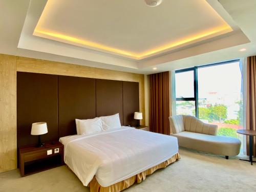 a bedroom with a large white bed and a chair at Muong Thanh Luxury Buon Ma Thuot Hotel in Buon Ma Thuot