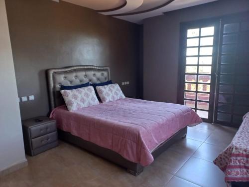 1 Schlafzimmer mit einem Bett mit einer lila Bettdecke und 2 Fenstern in der Unterkunft Villa piscine bir jdid in Bir Jedíd Saint-Hubert