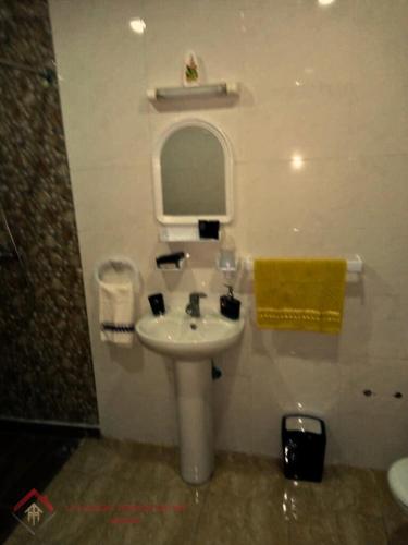 La salle de bains blanche est pourvue d'un lavabo et d'un miroir. dans l'établissement TARIK KHAYER, à Agadir