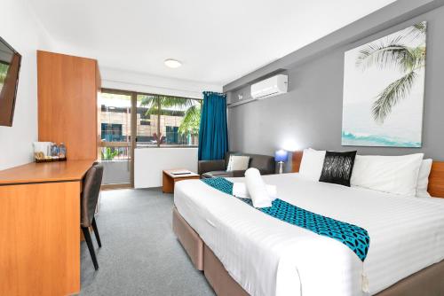 Habitación de hotel con cama grande y escritorio. en Peninsula Nelson Bay Motel and Serviced Apartments, en Nelson Bay
