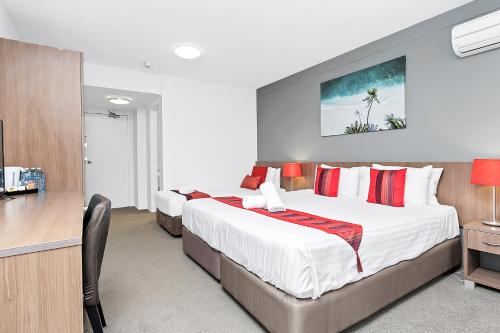 a hotel room with two beds and a desk at Peninsula Nelson Bay Motel and Serviced Apartments in Nelson Bay