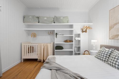 a white bedroom with a bed and a crib at Rigi on Currumbin Beach in Gold Coast