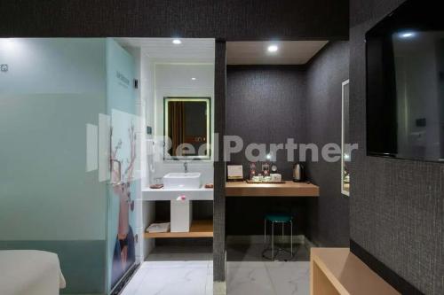y baño con lavabo y espejo. en Selecta Hotel Medan Petisah R Signature Mitra RedDoorz, en Medan
