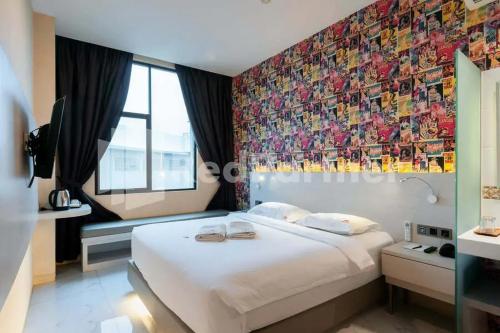 a bedroom with a large white bed with a colorful wall at Selecta Hotel Medan Petisah R Signature Mitra RedDoorz in Medan