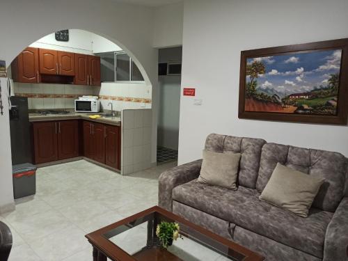 Una sala de estar con un sofá y una cocina. en Los Juanes apto con terraza, en Buga