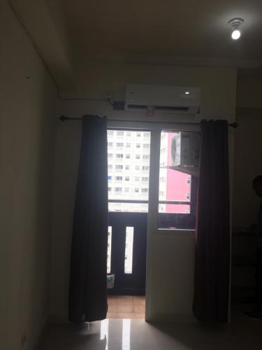 um quarto com uma janela e uma porta com cortinas em The Green Pramuka em Jakarta