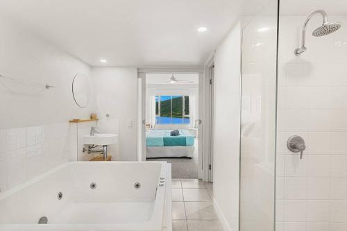 a white bathroom with a tub and a shower at Sea La Vie in Airlie Beach
