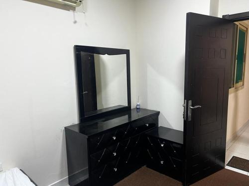 a black dresser with a mirror and a black door at Short Stay Apartment in Dubai