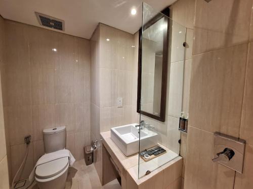 a bathroom with a white toilet and a sink at Horison Kuta Bali in Kuta