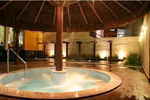 a hot tub in a building with an umbrella at Hot springs - suíte Premium in Caldas Novas
