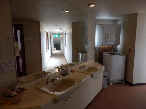 a large bathroom with two sinks and a hallway at Hotel Weisser Hof Happei in Hakuba