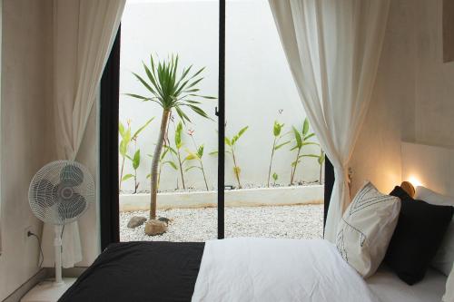 a bedroom with a bed and a window with a palm tree at Villa Soll B By The Villas 100 in Bogor