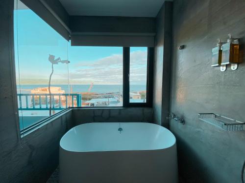 a bath tub in a bathroom with a view of the ocean at Lugo Hotel in Manzhou