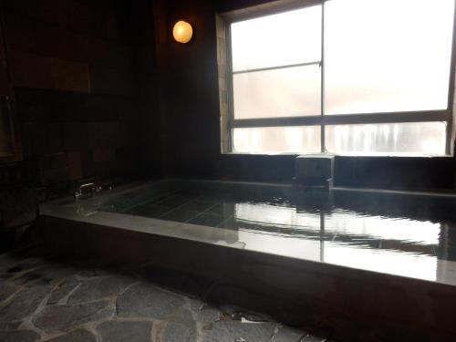 a bath tub in a room with a window at Hotel Weisser Hof Happei in Hakuba