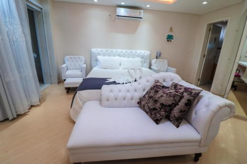 a bedroom with two white beds and a couch at Paraíso do Salto in Lages