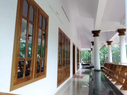 a corridor of a building with wooden doors and pillars at Kizhakkethottam Homestays-River View Villa in Pala