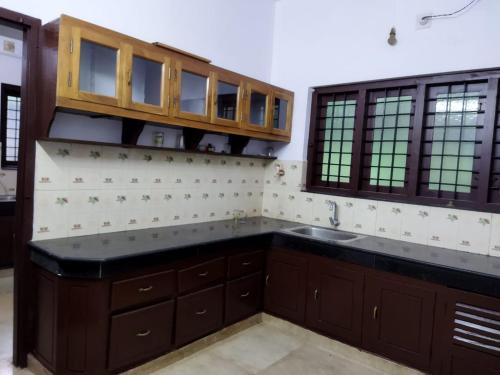 una cocina con armarios de madera y fregadero en Kizhakkethottam Homestays-River View Villa en Pala