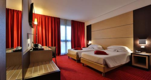 two beds in a hotel room with red curtains at Best Western Plus Hotel Galileo Padova in Padova