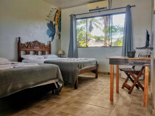 パラチにあるPousada Tropicália Paratyのベッドルーム1室(ベッド2台、デスク、窓付)