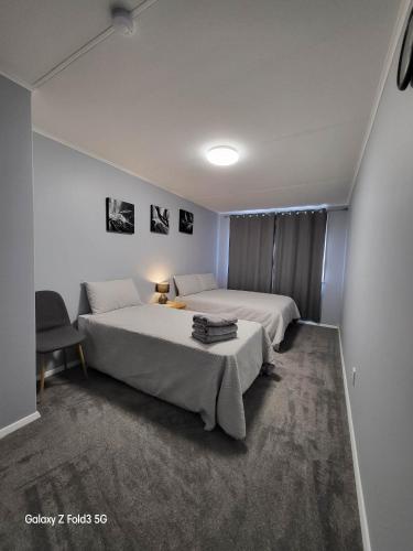 een slaapkamer met een groot wit bed en een stoel bij Stylish Homestay Close CBD in Hamilton