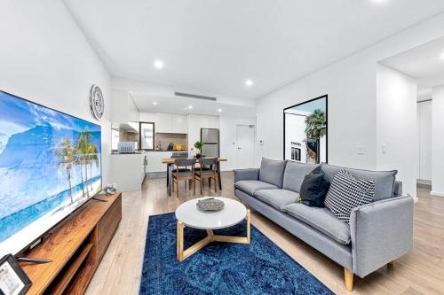 a living room with a couch and a large screen tv at Centre of Newtown 2 Bed Apartment in Sydney