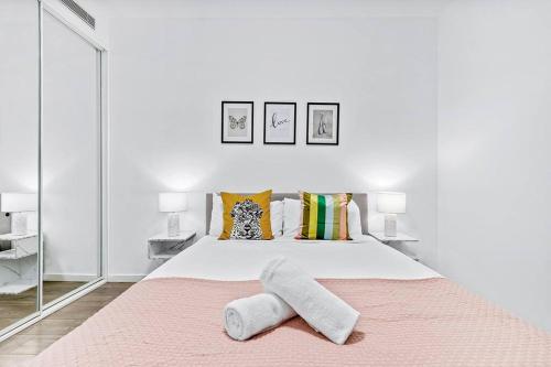 a white bedroom with a large bed with two towels on it at Centre of Newtown 2 Bed Apartment in Sydney