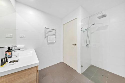 a white bathroom with a shower and a sink at Centre of Newtown 2 Bed Apartment in Sydney