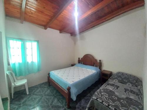 a bedroom with a bed and a chair and a window at Hospedaje Ale in Iruya
