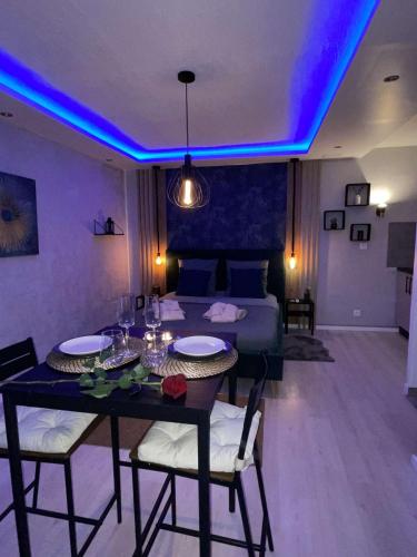 Cette chambre dispose d'une table à manger et d'un lit avec des lumières violettes. dans l'établissement Appartement La Splenzia SPA Jacuzzi wifi clim, à Avignon