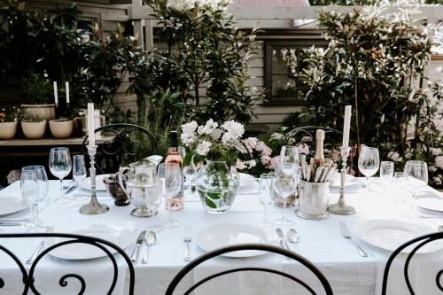 a white table with glasses and flowers on it at Jacks Garden Cottage at Poets Lodge in Daylesford