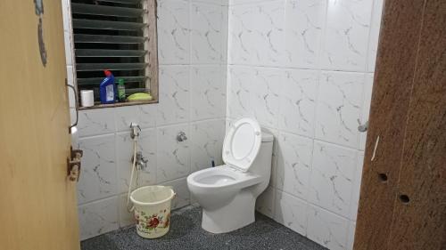 a bathroom with a white toilet and a bucket at RONNE'S Pamela 1BHK Apartment in Anjuna in Assagao