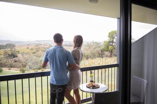 Ein Mann und eine Frau stehen auf einem Balkon mit Aussicht. in der Unterkunft Novotel Barossa Valley Resort in Rowland Flat