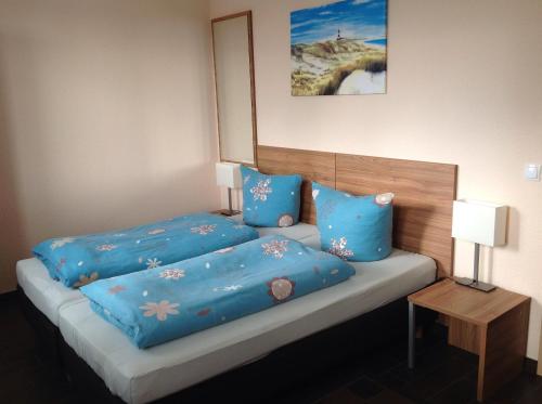 een slaapkamer met een bed met blauwe lakens en kussens bij Pension an der Werft II in Rostock