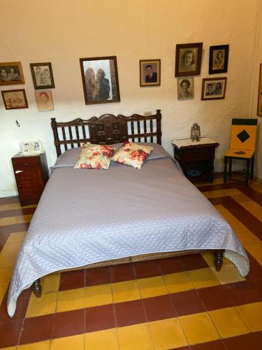 uma cama grande num quarto com fotografias na parede em Vivienda Turística - Casa de Carola em Jardín