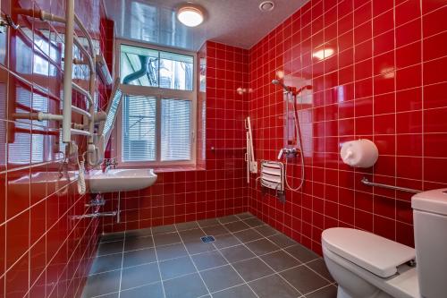 a red tiled bathroom with a toilet and a sink at Liberty in Rīga