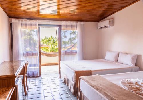 a room with two beds and a window with a balcony at PSP Resort All Inclusive in Porto Seguro