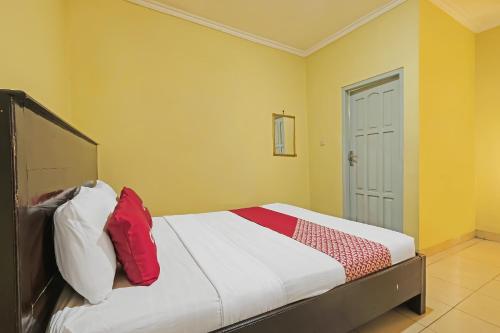 a bedroom with a bed with red and white pillows at OYO 92485 Hotel Family in Salatiga