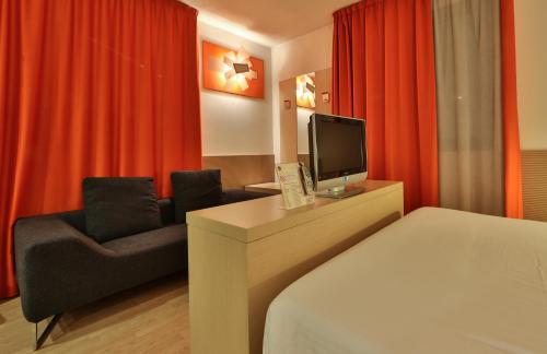 a hotel room with a bed and a tv and a chair at Best Western Plus Hotel Galileo Padova in Padova