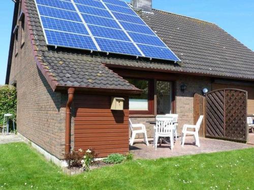 une maison dotée d'un toit solaire avec une table et des chaises dans l'établissement Ferienhaus "Haus Fasanenwiese" - SORGENFREIES REISEN, à Friedrichskoog-Spitz