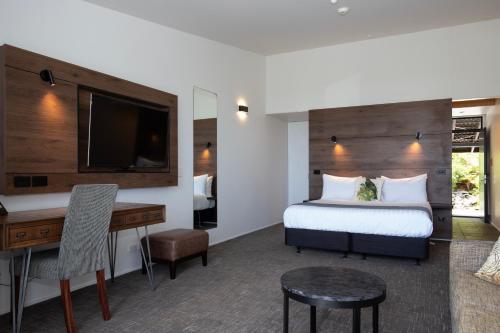 a hotel room with a bed and a desk and a television at Scenic Hotel Punakaiki in Punakaiki
