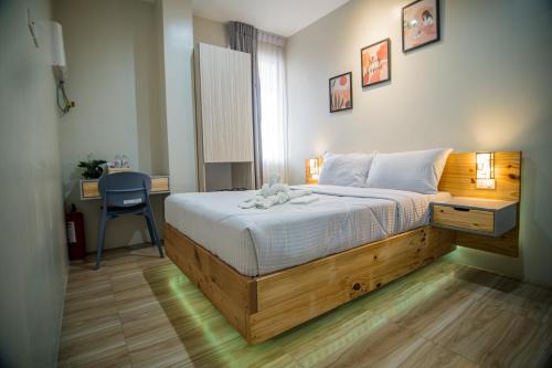 1 dormitorio con 1 cama grande con marco de madera en DLT Suites Boutique Hotel, en Minglanilla