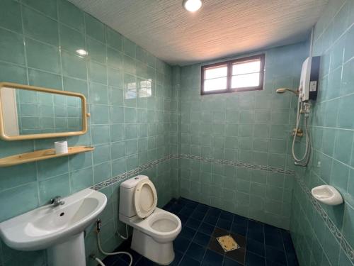 a bathroom with a toilet and a sink and a mirror at Baan Wang Bua in Ban Khok Kroat