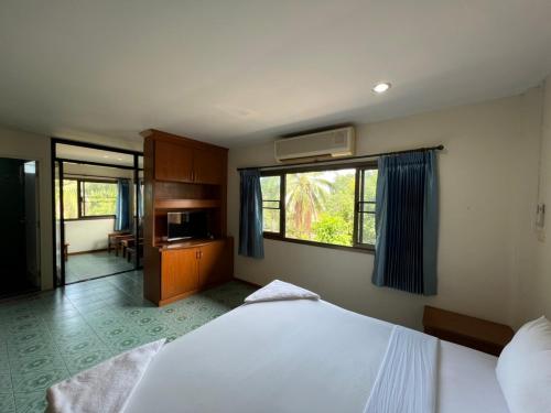 Un dormitorio con una gran cama blanca y una ventana en Baan Wang Bua, en Ban Khok Kroat