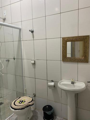 a white tiled bathroom with a sink and a mirror at Apartamento em frente Basílica 1 in Aparecida