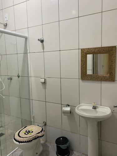 a white tiled bathroom with a sink and a mirror at Apartamento em frente Basílica in Aparecida